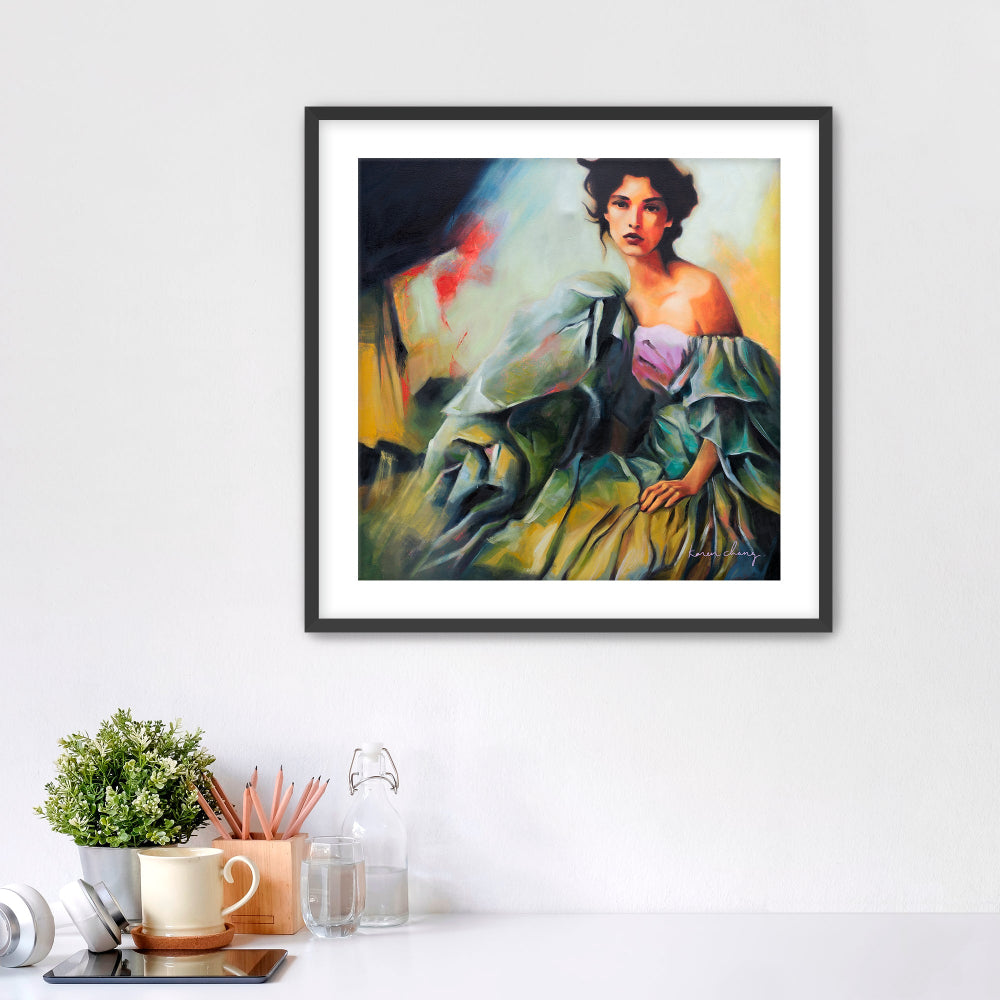 Framed painting of a woman in a green dress on a white wall above a desk.