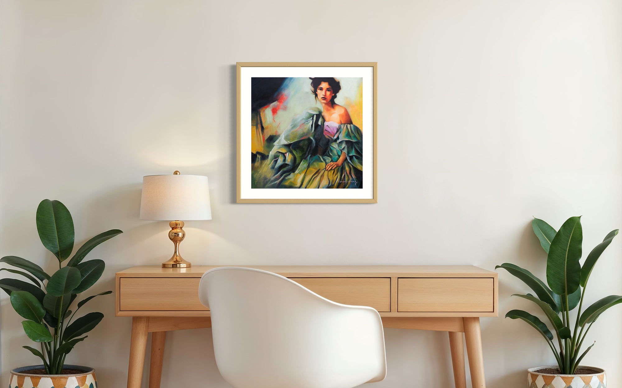 Framed painting on a wall above a wooden desk with a chair and plants.