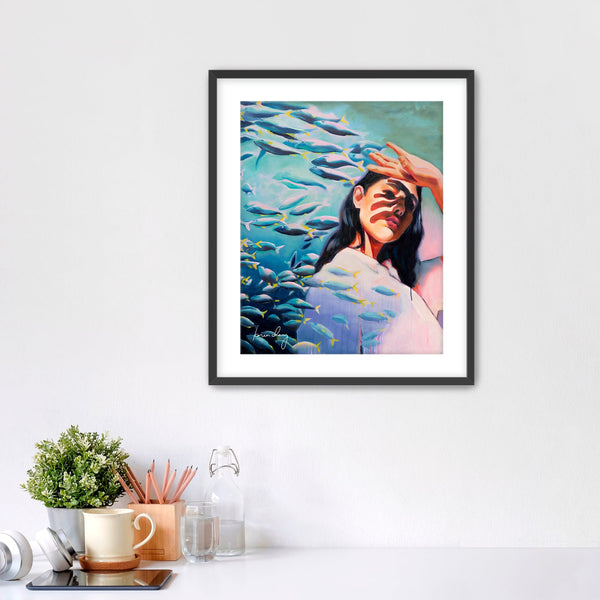 Framed artwork of a woman surrounded by fish on a white wall.