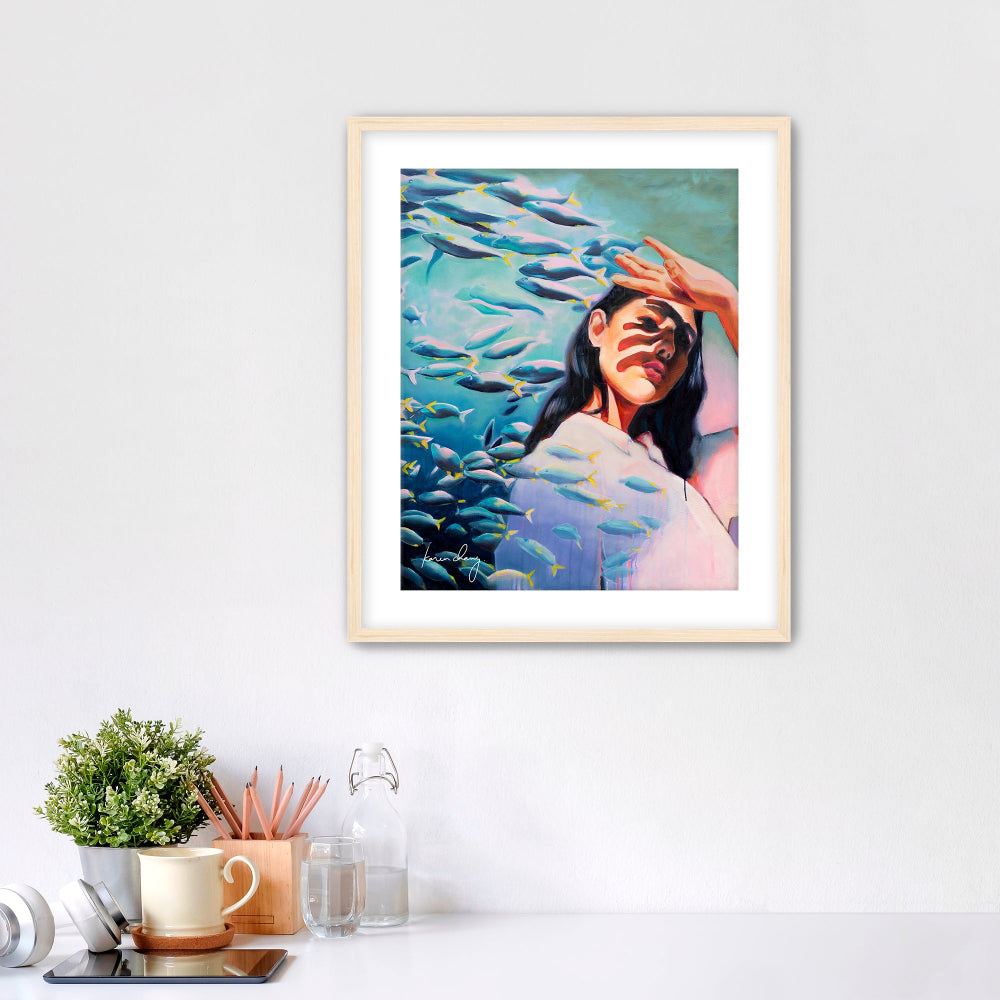 Framed artwork of a woman surrounded by fish on a white wall.