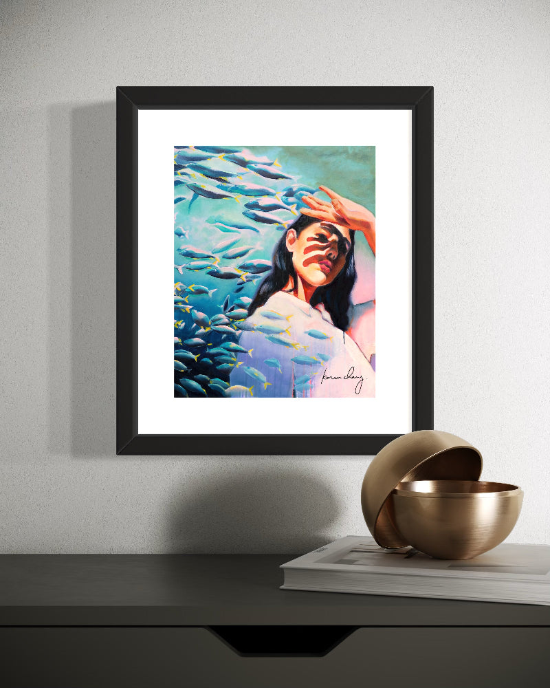 Framed artwork of a woman surrounded by fish on a wall above a shelf with decorative items.