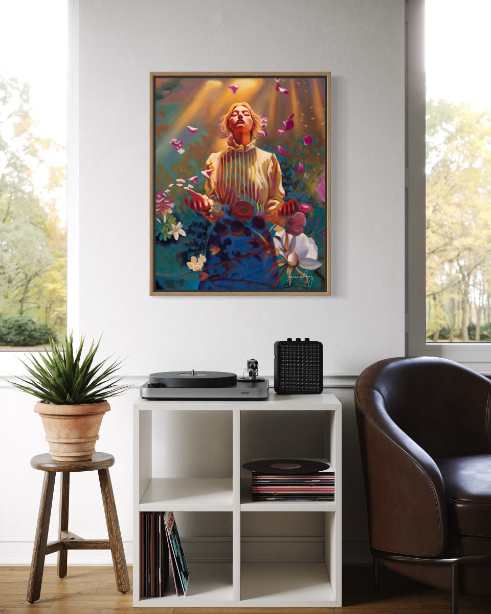 Framed artwork on a wall above a record player with a plant and chair in the room.