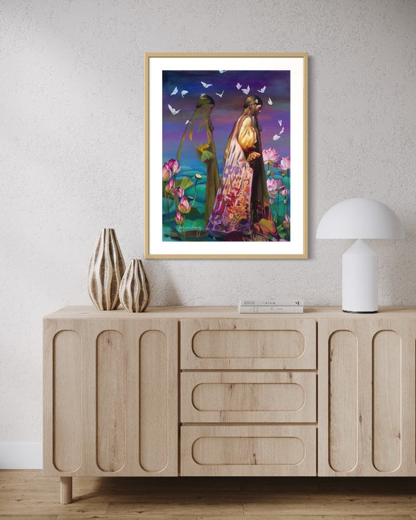 Framed artwork of two women in a garden with butterflies on a wall above a wooden cabinet.