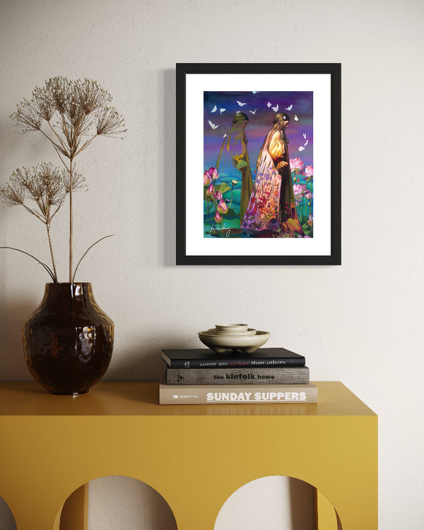 Framed artwork on a wall above a yellow table with books and a vase.