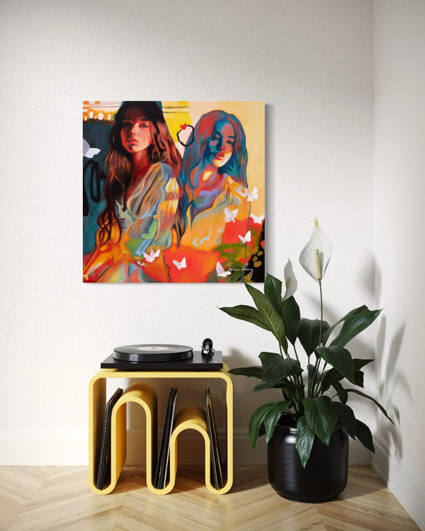 Colorful abstract painting of two women on a wall above a yellow stool with a plant next to it.