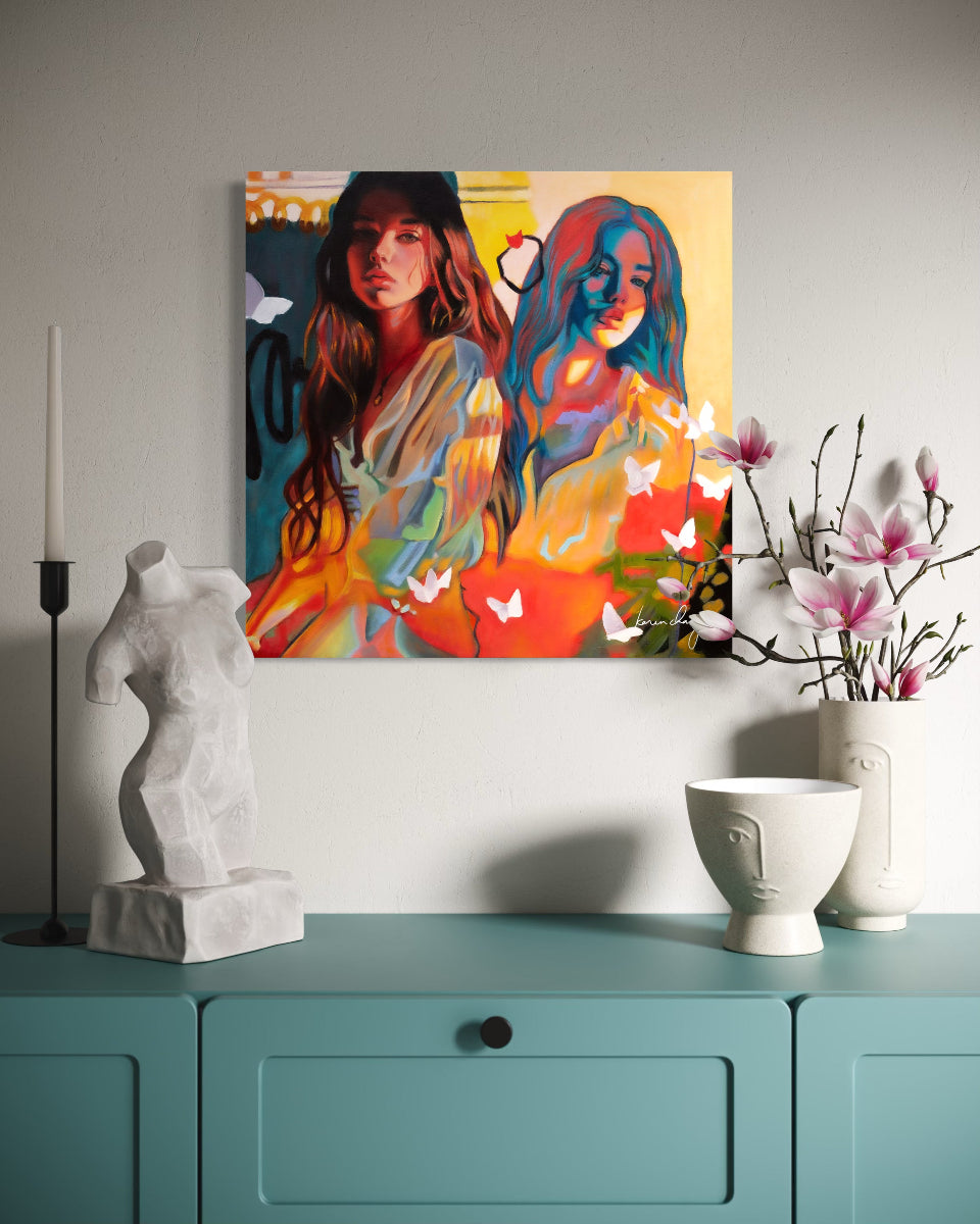 Colorful abstract painting of two women on a wall above a teal cabinet with decorative items.