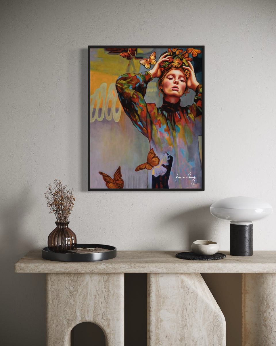 Framed artwork of a woman with tattoos and butterflies on a wall above a console table.
