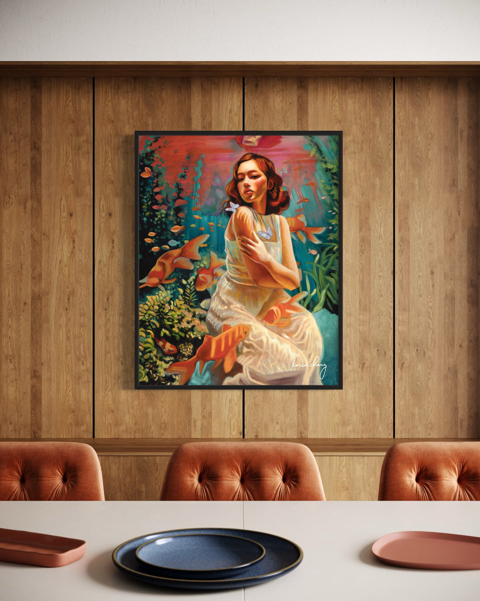 Framed artwork of a woman with fish in a room with wooden paneling and a dining table.