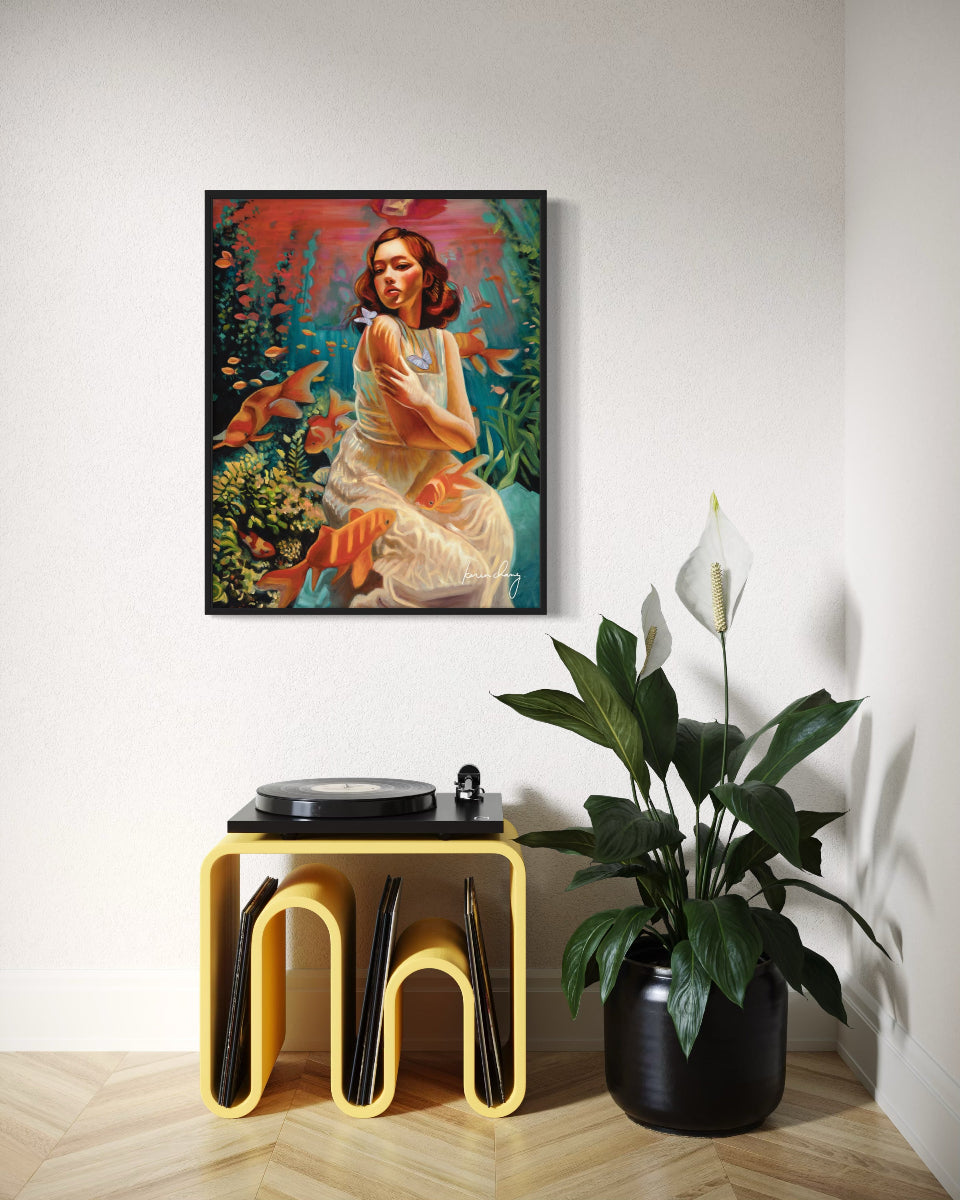 Framed artwork of a woman with fish in a room with a yellow stool and plant.